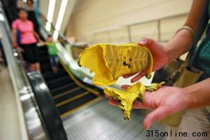 昨日下午,劉女士在出事扶梯前展示兒子被夾壞的涼鞋。本報記者 王貴彬 攝