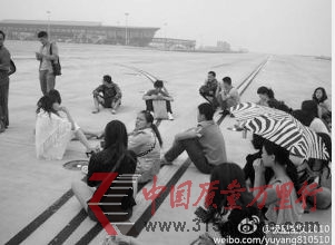 網友@極品寶貝2010在微博上貼出乘客圍坐機場跑道的照片
