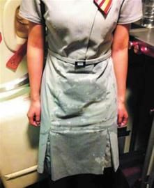 一名身著空乘制服的女子,其腰部以下的裙擺上布滿水跡